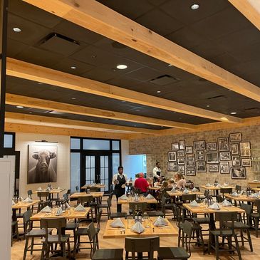 Modern restaurant interior with wooden beams and framed photos on the wall.