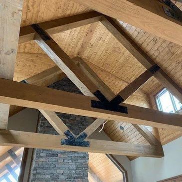 Exposed wooden beams and trusses on a vaulted ceiling with metal connectors.