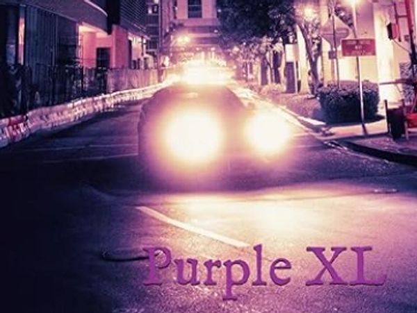 Nighttime city street illuminated by car headlights and purple lighting.