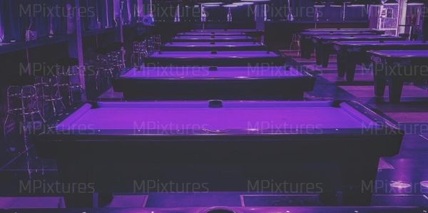 Pool tables in a dimly lit room with purple lighting.