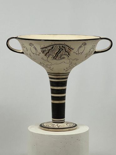 Tall black-painted kylix with handles. Lundehund dog stands at base of cliff flanked by two puffins.