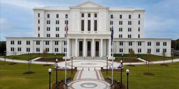 White courthouse building with columns and a circular driveway.