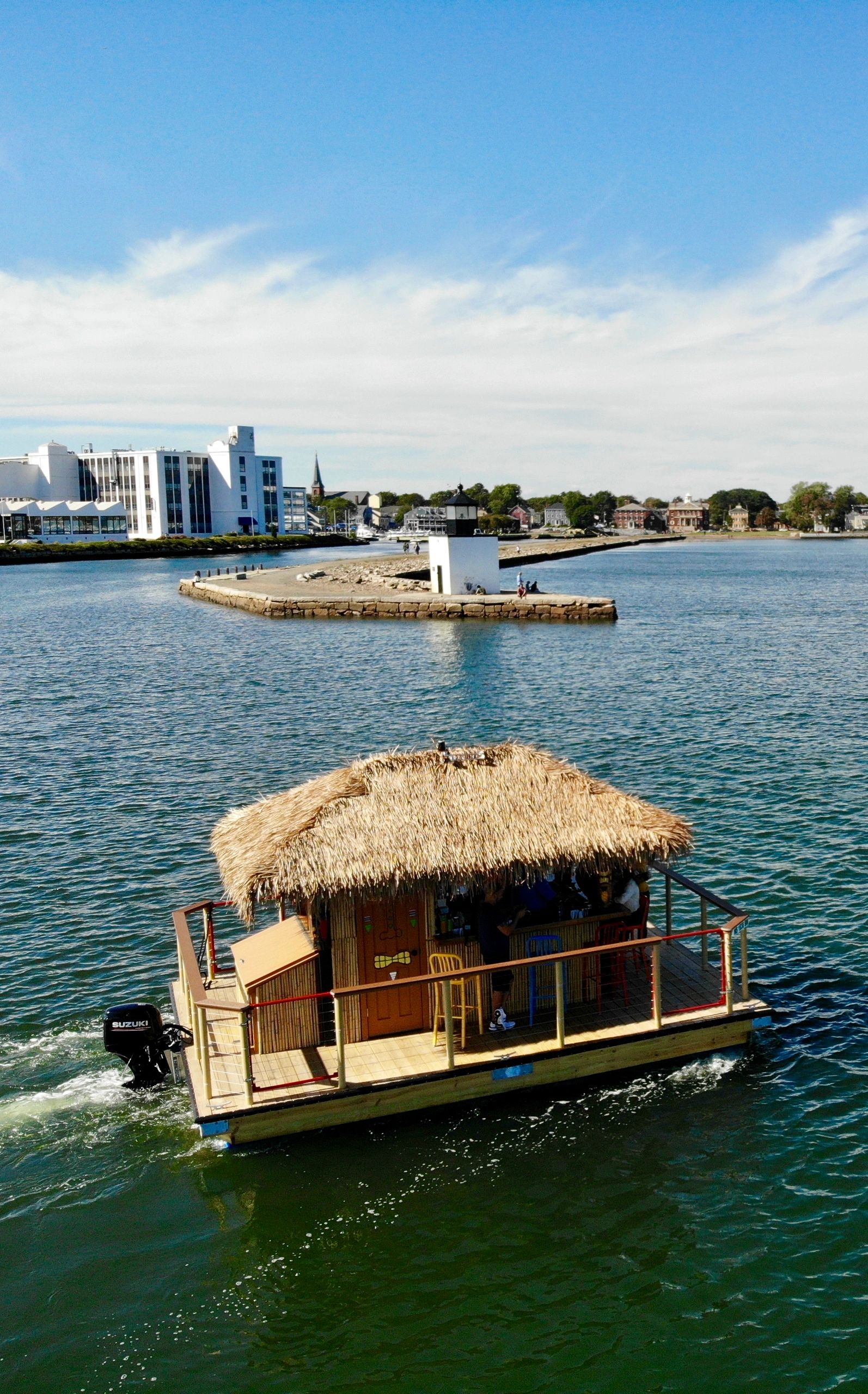 Tiki Hut Boat on ocean by lighthouse.