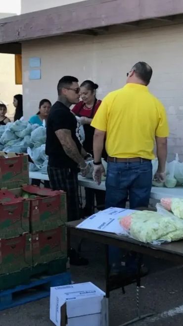 Volunteers distributing food packages at an outdoor event.