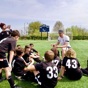 A youth soccer coach talks to his team during a break on the field.