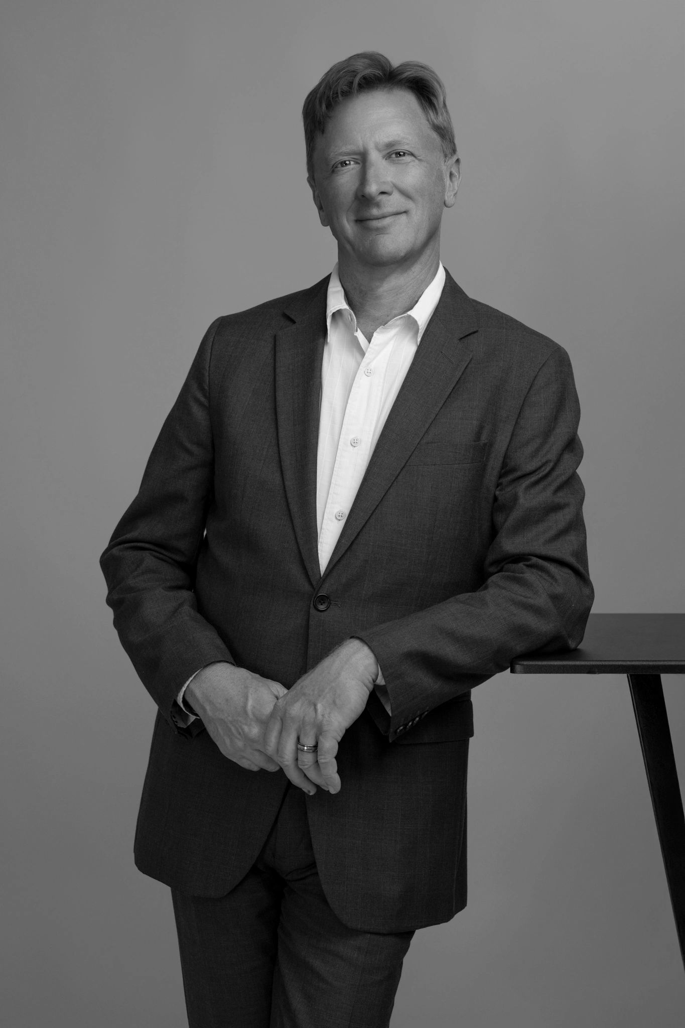 Smiling man in a suit posing against a plain backdrop.