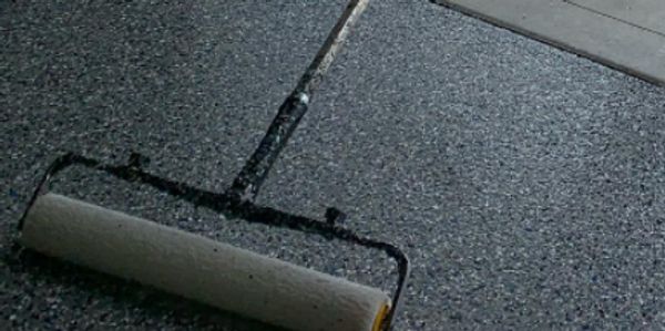 Rolling the polyaspartic topcoat is the final step for a quality epoxy garage floor.