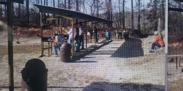 People at an outdoor shooting range on a sunny day.