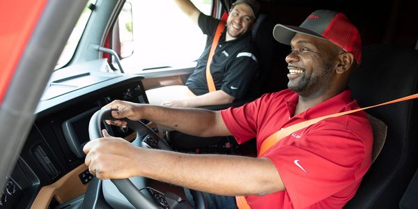 Two men smiling inside a truck cabin.