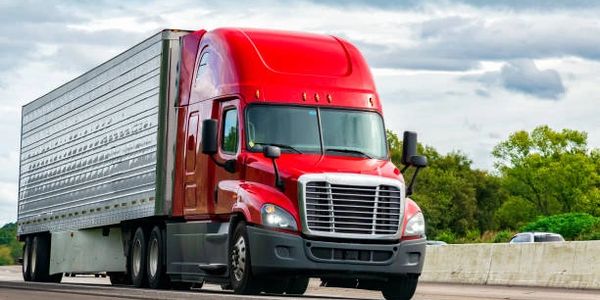 Red semi-truck driving on a highway.