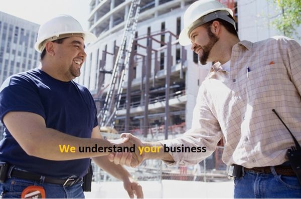 Two construction workers shake hands at a building site, showing teamwork.