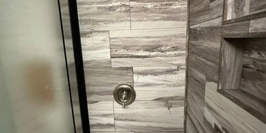 Shower with a metal handle and marble tiles.
