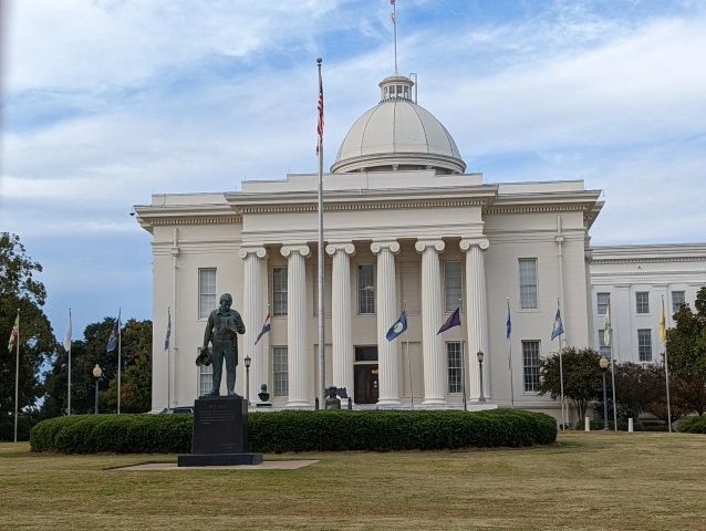 Historic white government building with columns and statue.
