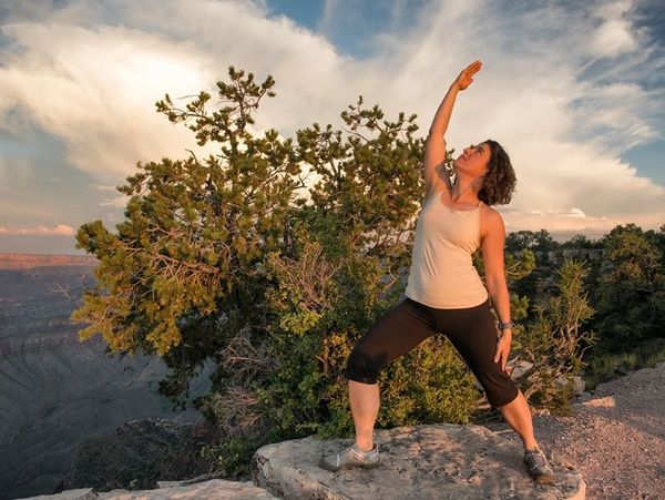 Woman doing yoga outdoors on rocky terrain.