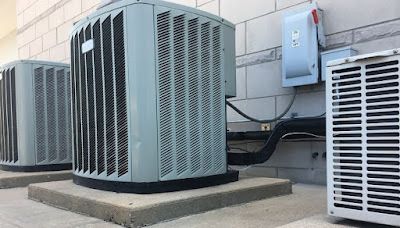 Three outdoor HVAC units on concrete slabs.