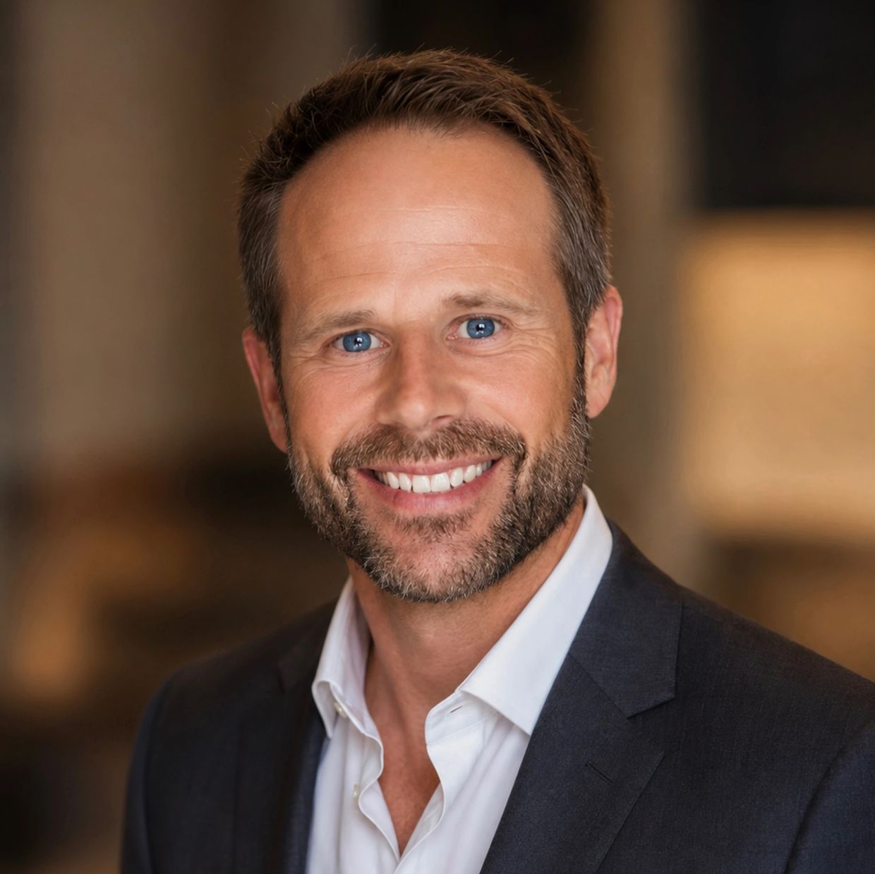 Smiling man in business attire with blue eyes.