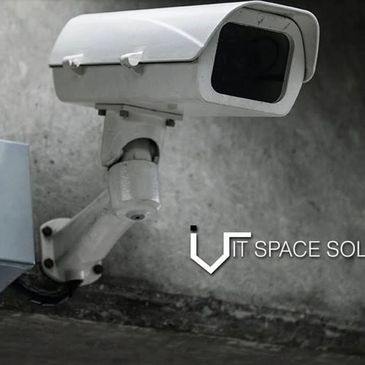 White security camera mounted on a wall with IT Space Solutions logo.