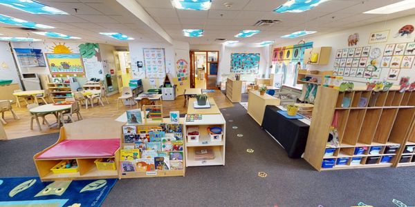Colorful and organized preschool classroom with educational materials and kid-sized furniture.
