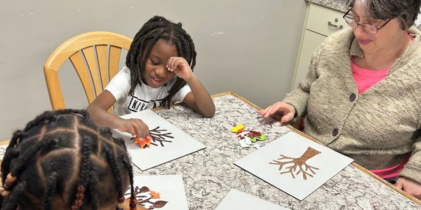 Children doing a tree craft with an adult supervisor.