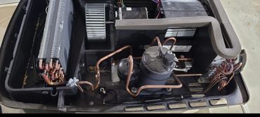 Internal components of an air conditioning unit with copper tubing and a compressor.