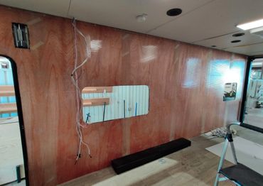 Interior wall with wooden paneling and a cut-out window under construction.