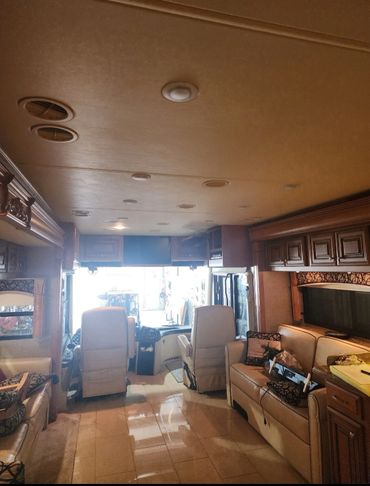 Interior of a spacious RV with leather seats and wooden cabinets.