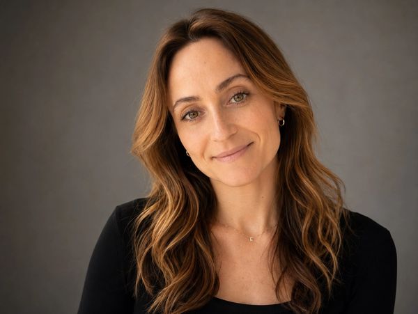 Smiling woman with wavy brown hair in black top.