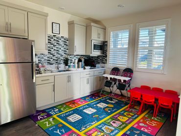 Bright kitchen corner with colorful children's rug and red table set.