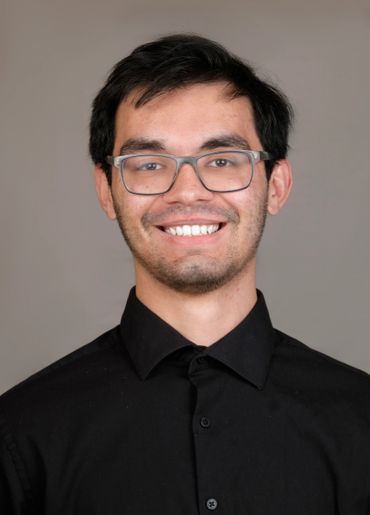 headshot young man glasses black shirt studio portrait