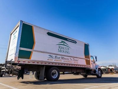 A Rise Up Moving truck parked under a clear blue sky.