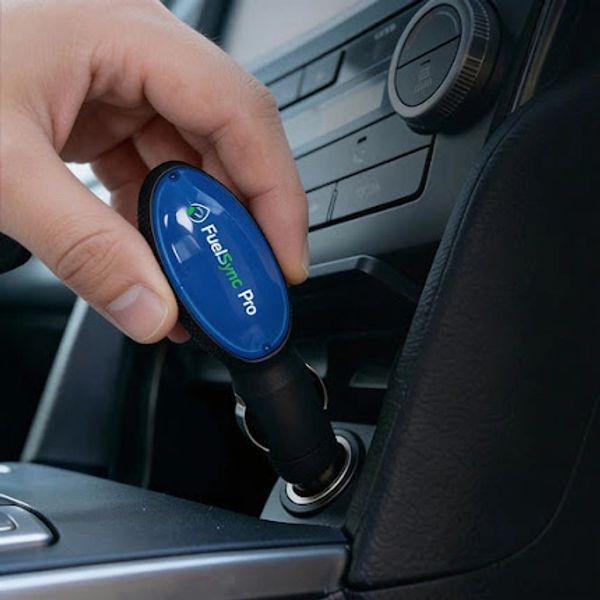 Hand inserting a FuelSync Pro device into a car's cigarette lighter port.