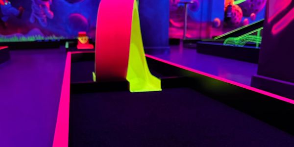Neon-lit mini golf course with glowing cosmic-themed obstacles.