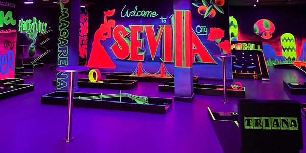 Neon-lit indoor mini golf with vibrant Seville-themed murals and playful decorations.