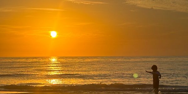 Child playing at the beach during a golden sunset.