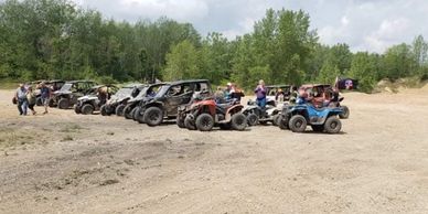 Large group of side by sides on sand.