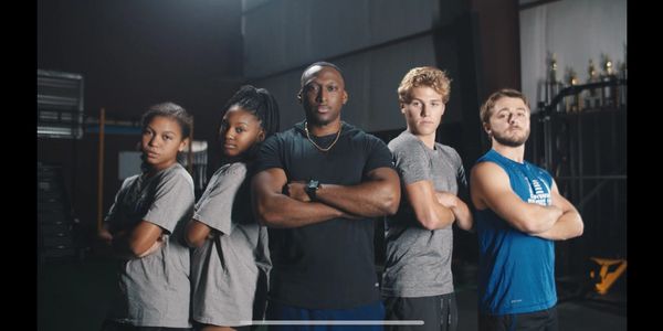 Five athletes stand confidently with arms crossed in a gym setting.