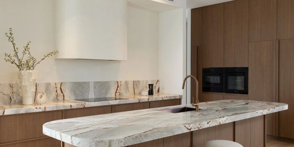 Modern kitchen with marble countertops and wooden cabinetry.