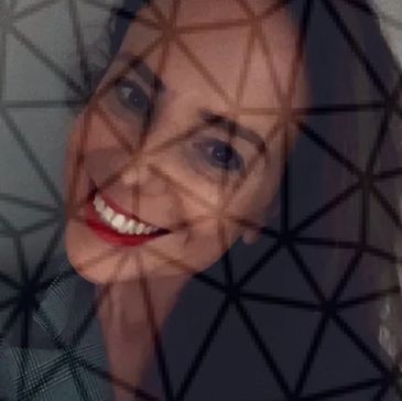 A woman smiling behind a geometric patterned screen.