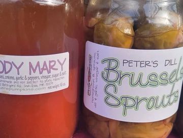 A jar of pickled brussel sprouts on a table.