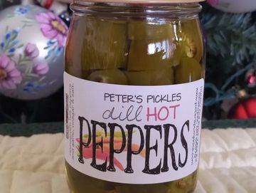 A jar of pickled peppers with a label that has a pickle logo.