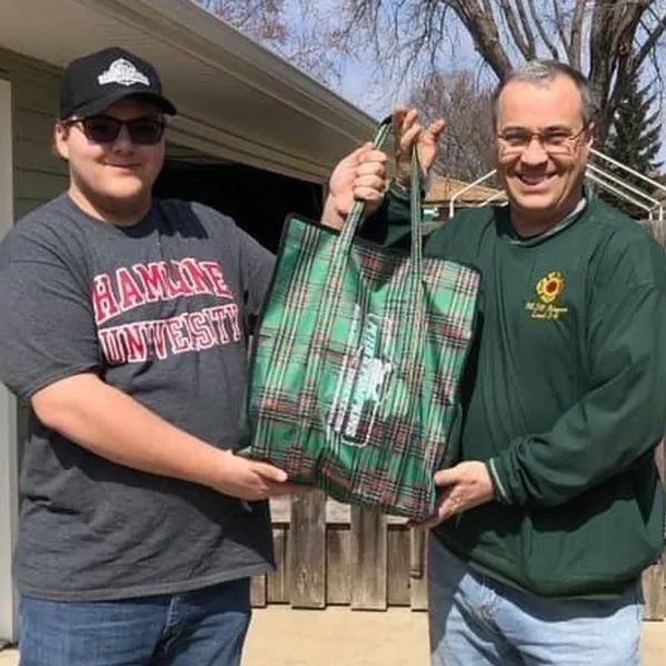 Two persons posing with a bag full of vegetables