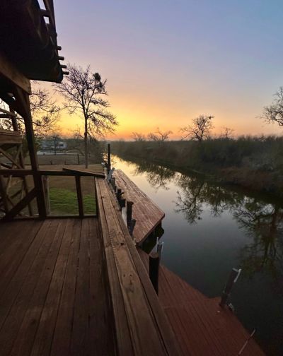 Wooden balcony overlooking a calm river at sunset.