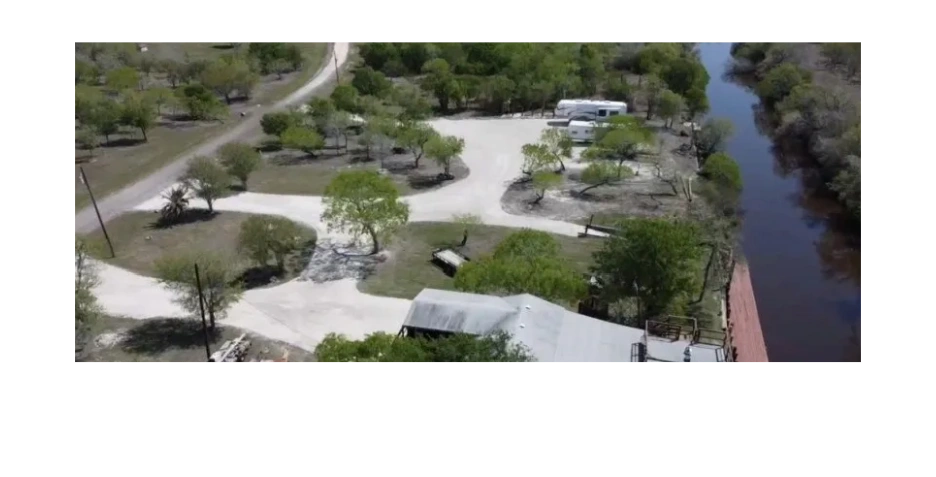 Scenic riverside campground with RVs and dining area.