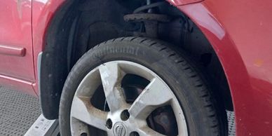 Close-up of a car's dirty wheel and tire on a red vehicle.