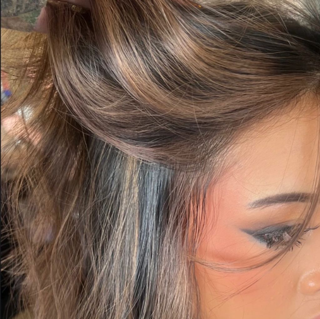 Close-up of brown hair with highlights and eye makeup.