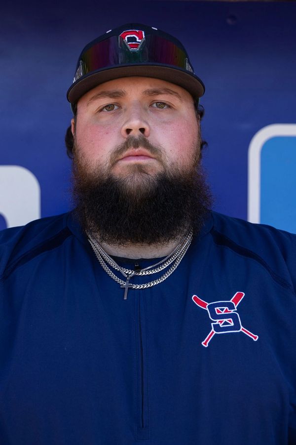 Bearded baseball player wearing team gear and chains.