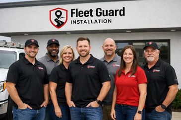 Team of seven Fleet Guard Installation employees posing outside their office.