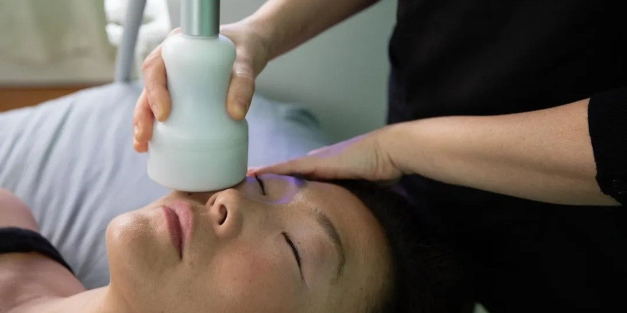 A woman receiving a facial treatment with a handheld device.
