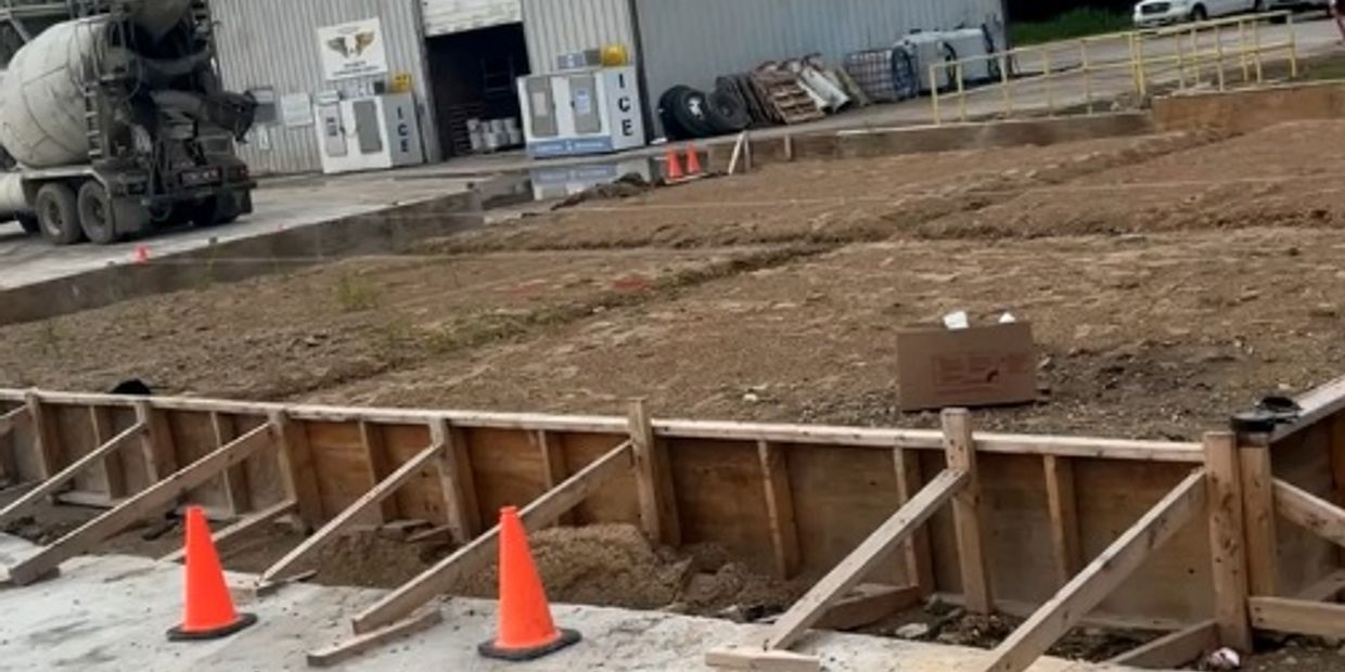 Construction site with soil preparation and wooden formwork with orange cones.