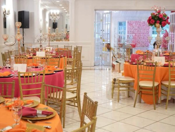 Elegant banquet hall decorated with orange and pink table settings.